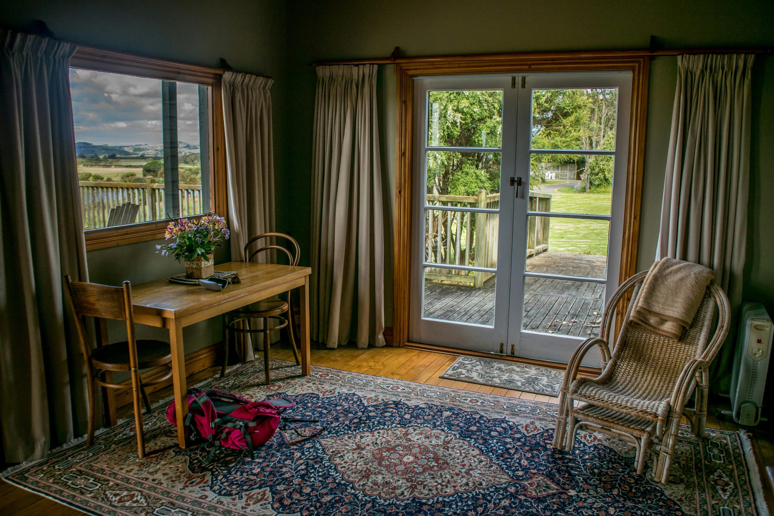 A charming room with vintage decor and a view of a lush garden through open doors.